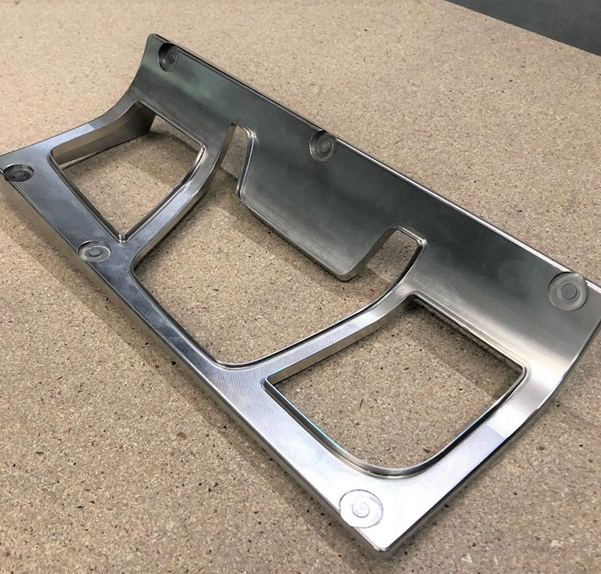 In ein gebogenes Werkstück aus Edelstahl wurden verschiedene Öffnungen gefräst.