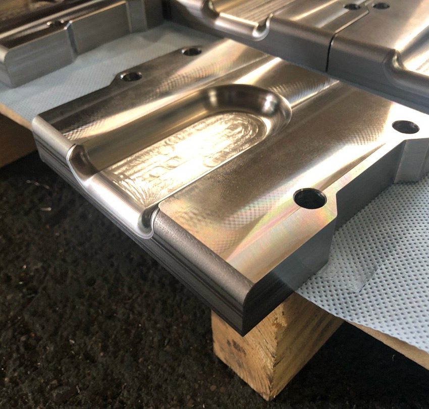 Ein Werkstück mit gefrästen Aussparungen und Öffnungen liegt auf einer Holzpalette.