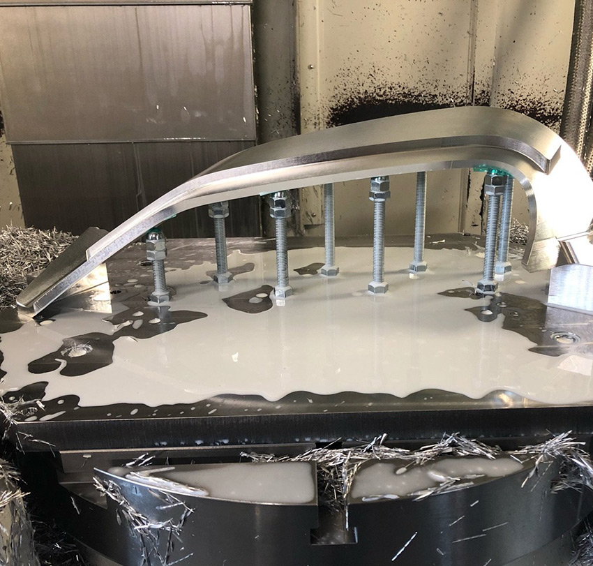 Ein gebogenes Werkstück mit unterschiedlich hohen Ebenen unmittelbar nach der Bearbeitung durch die Fräse